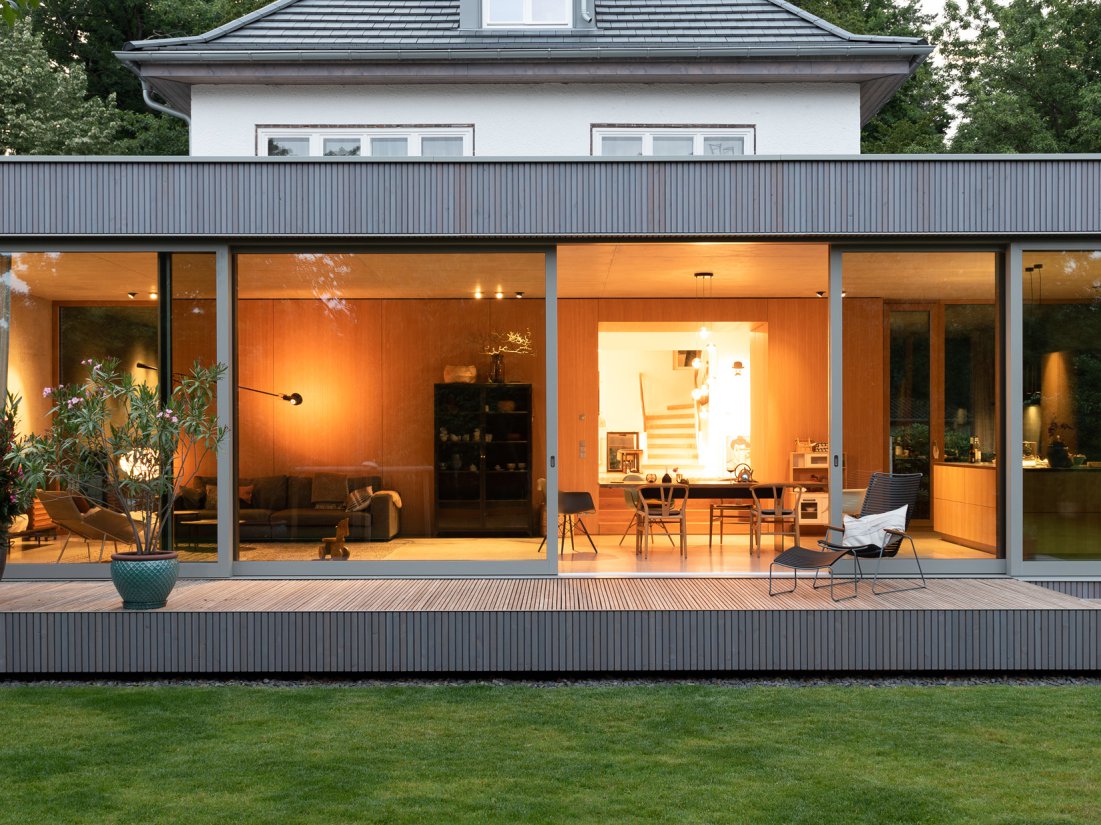 Minimalistischer Wohnpavillon aus Sichtbeton großzügiger Glasfassade, Terrazzoboden und echholzfurnierten Einbaumöbeln in Eiche natur.