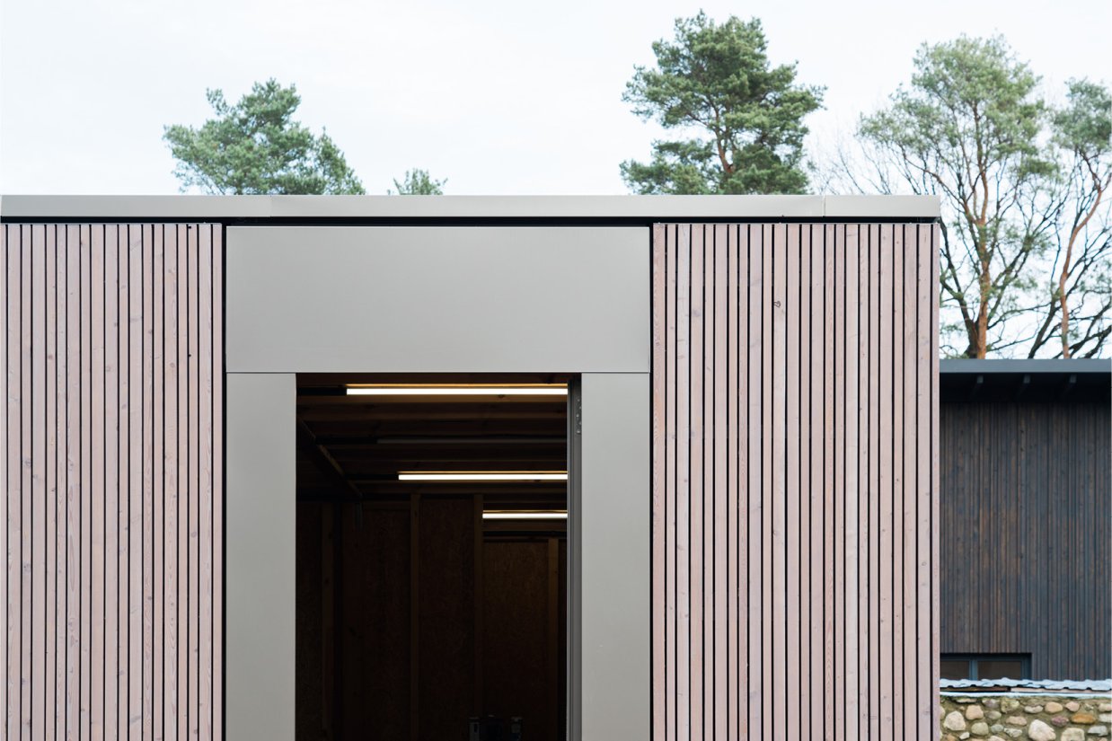 Detail der Holz-Aluminum-Türen an der rhythmisierten Fassade aus vergrautem Lärchenholz