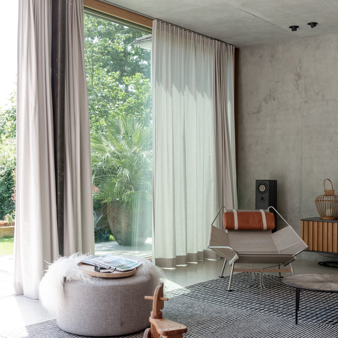 Minimalistischer Wohnbereich aus Sichtbeton, Terrazzoboden und großzügiger Hebe-Schiebeanlage mit Eichenrahmen von Bonauer Bölling Architekten.