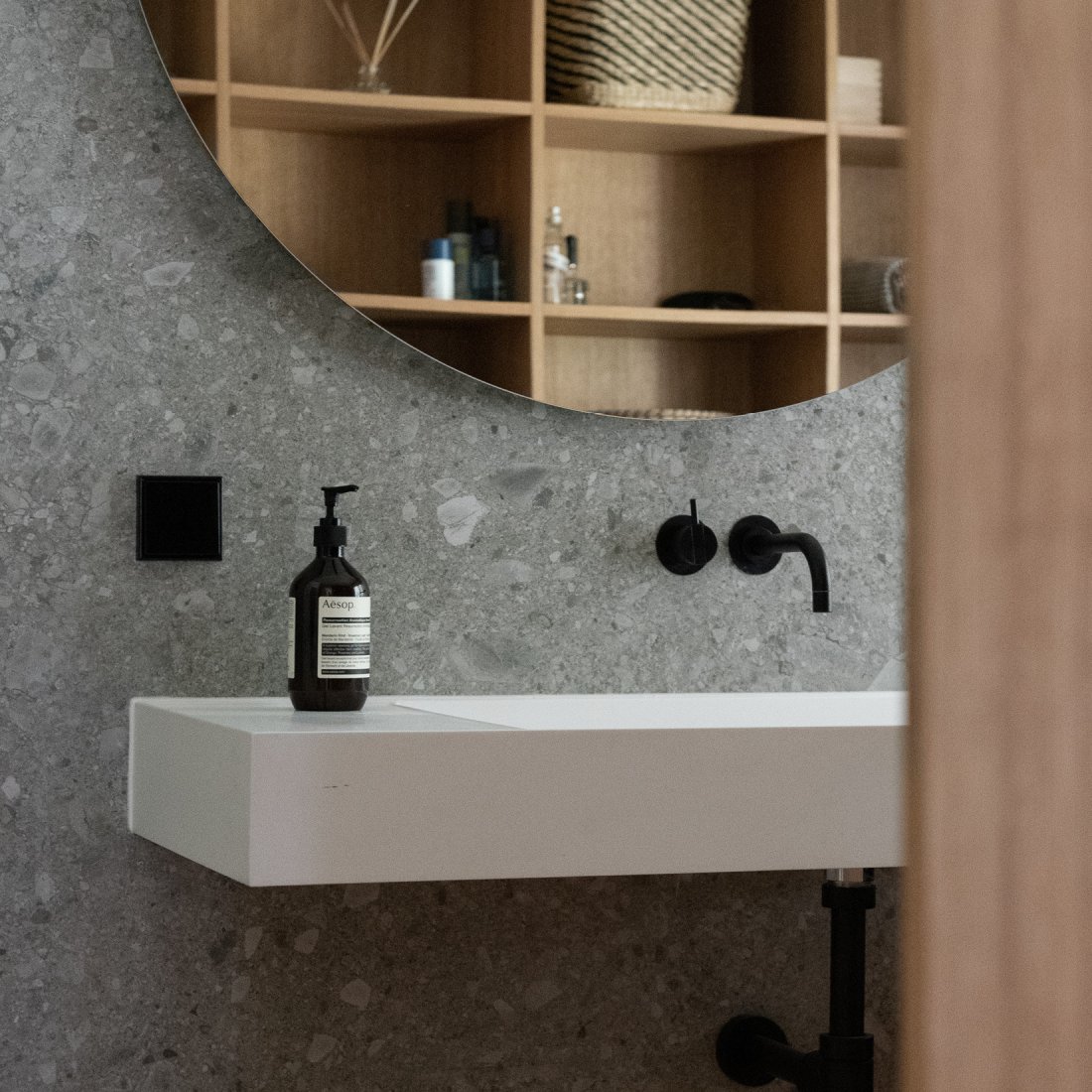 Design Bad mit weissem Waschtisch und schwarzer Vola Armatur.