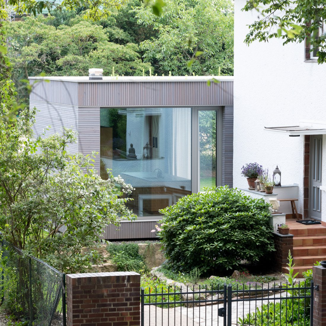 Minimalistischer Erweiterungsbau aus Beton und Holz mit restauriertem Bestandswohnhaus im Vordergrund von Bonauer Bölling Architekten.
