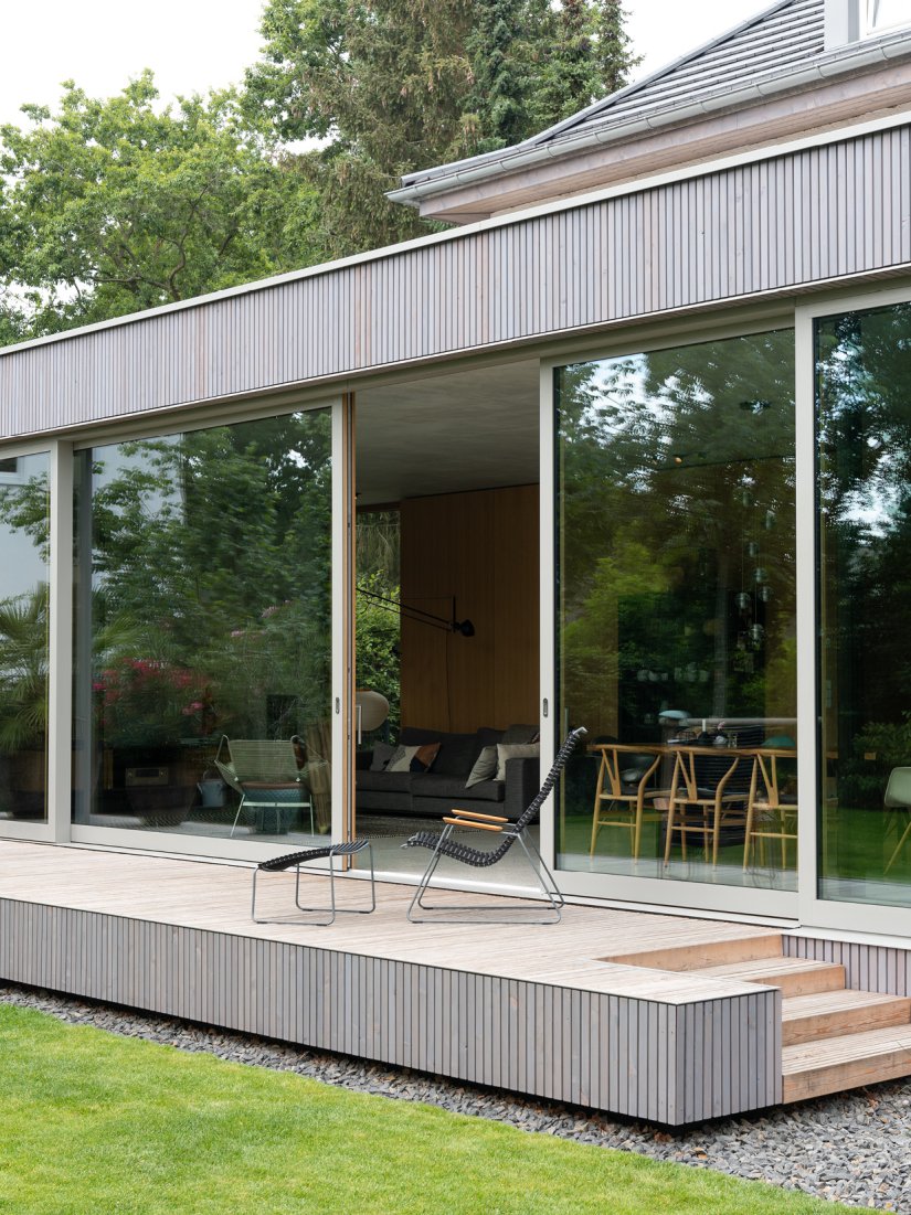 Minimalistischer Wohnpavillon aus Sichtbeton mit Holzdeck aus sibirischer Lärche und großzügiger Glasfassade.