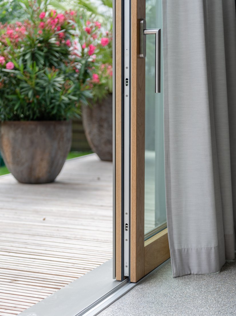 Detail Hebe-Schiebe-Anlage mit Holzrahmen aus Eiche, FSB Edelstahlgriff, Terrazzoboden und Terrassendeck aus sibirischer Lärche. 