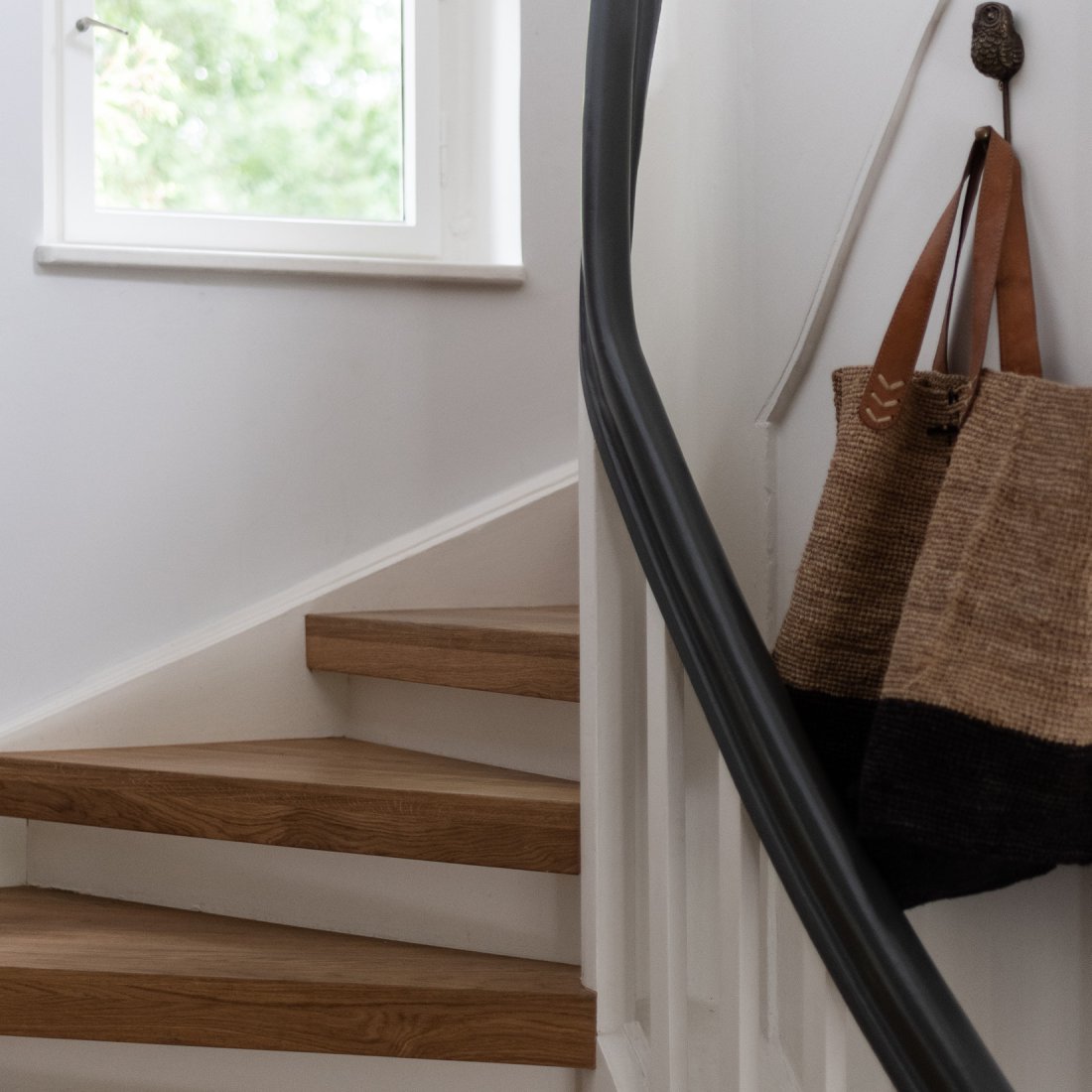 Restaurierte Bestandstreppe mit weiss lackiertem Handlauf und Stufen aus Massivholz in Eiche Natur.