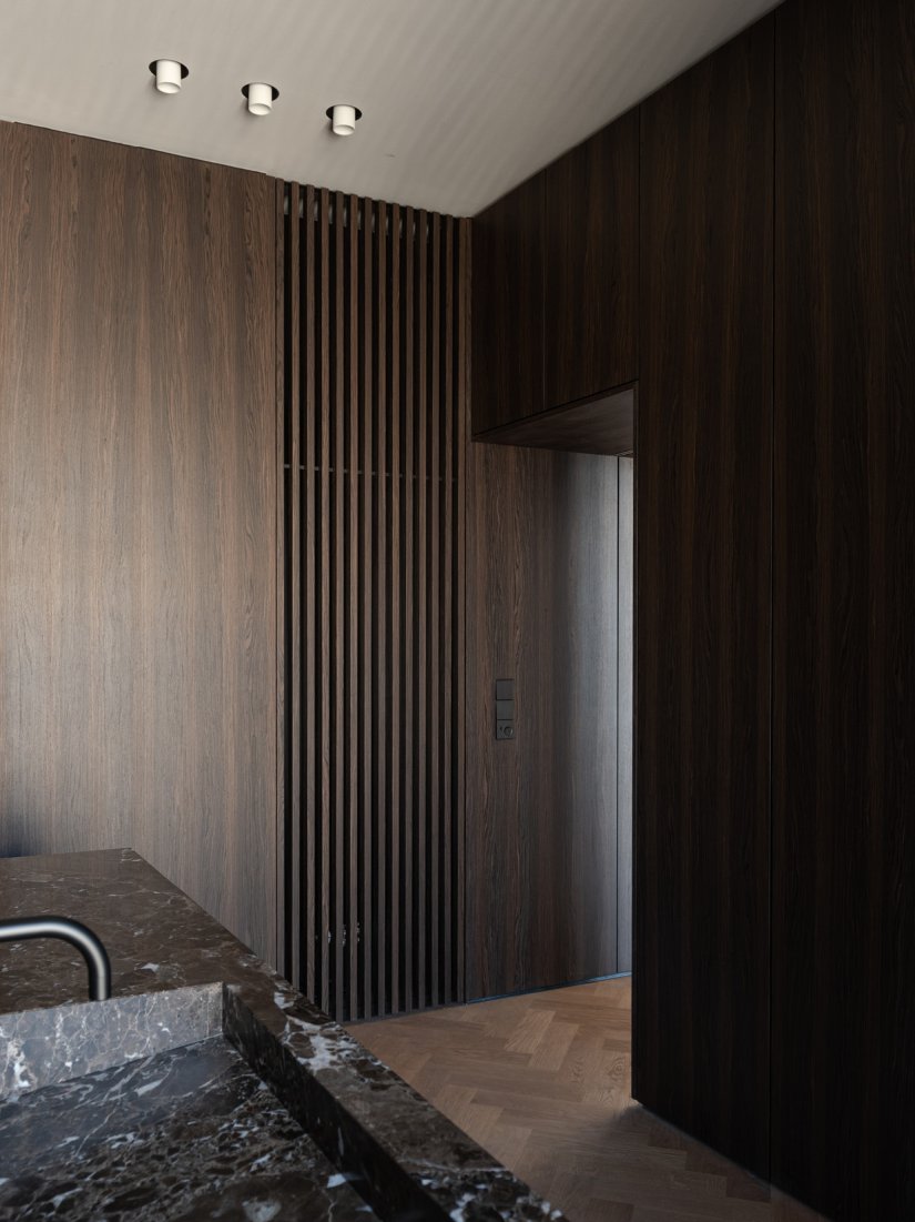 Masterbad mit maßgefertigten Einbauschränken aus Räuchereiche und Marmorwaschtisch aus Emperador Marron mit schwarzer Vola Armatur