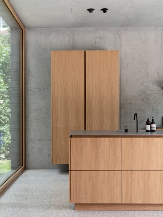 Maßgefertigter Hochschrank und Kücheninsel mit echtholzfurnierten Oberflächen in Eiche Natur und mattierter Edelstahl-Arbeitsplatte Silver Touch von Stadler Edelstahl.